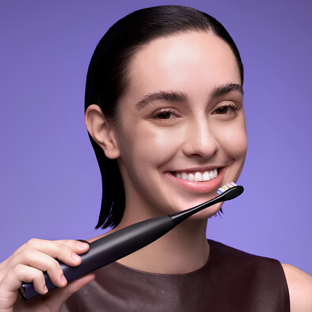Distribuidores cuidado personal. Chica sonriente utilizando el cepillo de dientes negro de Oclean